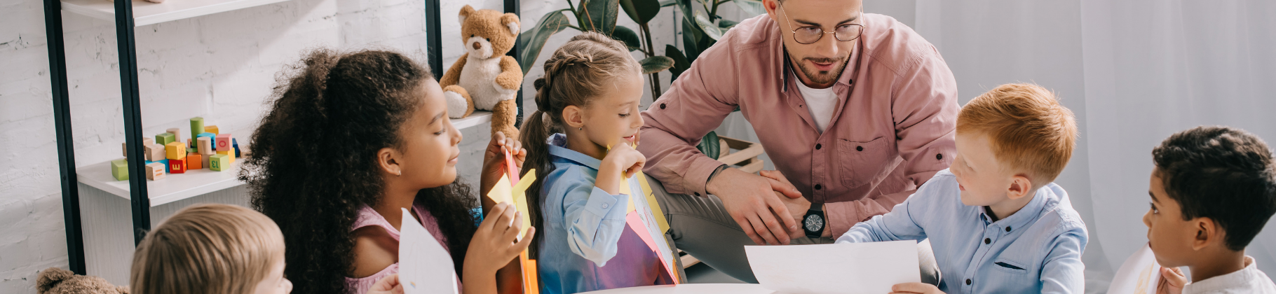 male teacher with young students at a table